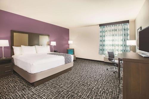 a hotel room with a bed and a flat screen tv at La Quinta by Wyndham Dallas Plano - The Colony in The Colony