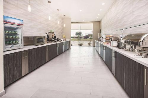 a large kitchen with a long counter in a restaurant at La Quinta by Wyndham Dallas Plano - The Colony in The Colony