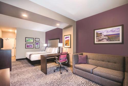 a hotel room with a bed and a desk and a couch at La Quinta by Wyndham Clifton Park in Clifton Park