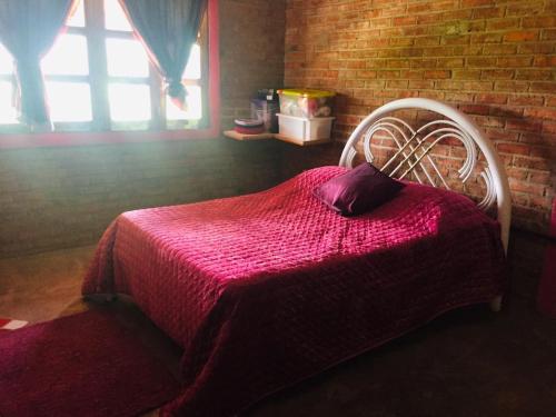 a bedroom with a bed with a red blanket and a window at Chalé com Vista Privilegiada in Pilões