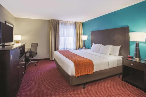 a hotel room with a bed and a flat screen tv at La Quinta by Wyndham O'Fallon, IL - St. Louis in O'Fallon