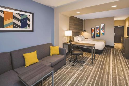 a hotel room with a bed and a couch and a desk at La Quinta Inn & Suites by Wyndham Atlanta South - McDonough in McDonough