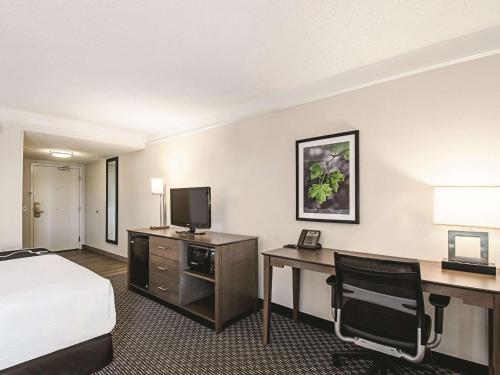 a hotel room with a bed and a desk with a television at La Quinta by Wyndham Cincinnati Sharonville in Sharonville
