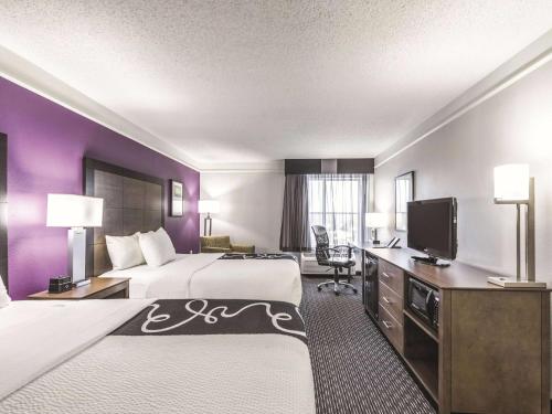 a hotel room with two beds and a flat screen tv at La Quinta by Wyndham Cincinnati Sharonville in Sharonville