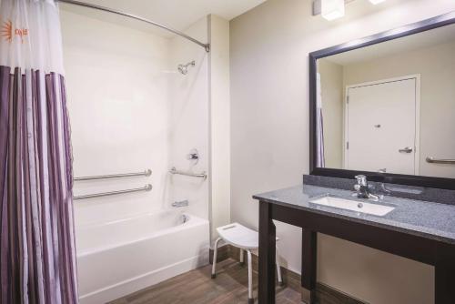 a bathroom with a sink and a tub and a mirror at La Quinta by Wyndham Clifton Park in Clifton Park