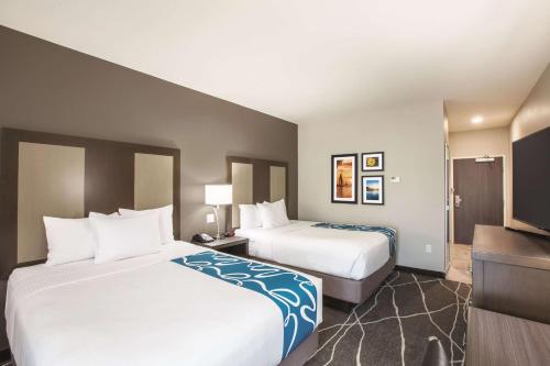 a hotel room with two beds and a flat screen tv at La Quinta by Wyndham Tulsa Broken Arrow in Broken Arrow