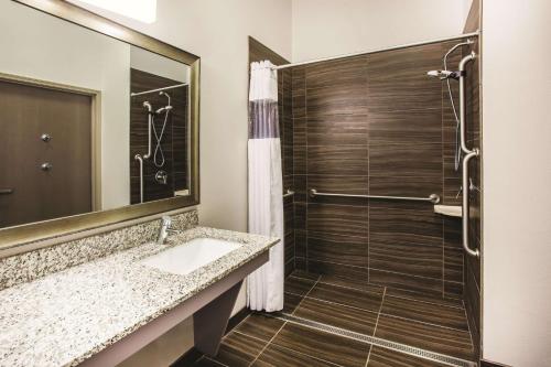 a bathroom with a shower and a sink and a mirror at La Quinta by Wyndham St. Paul-Woodbury in Woodbury