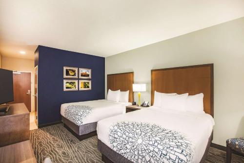 a hotel room with two beds and a bathroom at La Quinta by Wyndham Wichita Northeast in Wichita
