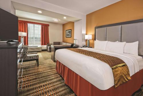 a hotel room with a large bed and a desk at La Quinta by Wyndham San Antonio by Frost Bank Center in San Antonio