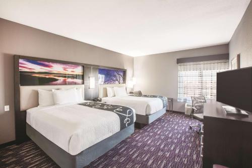 a hotel room with two beds and a flat screen tv at La Quinta by Wyndham Kingsville in Kingsville