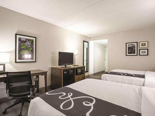 a hotel room with two beds and a desk and a television at La Quinta by Wyndham Baltimore N / White Marsh in Baltimore