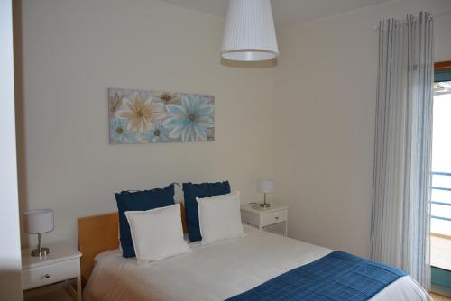 een slaapkamer met een bed met blauwe en witte kussens bij Stunning Apartment with Marina Views in Albufeira