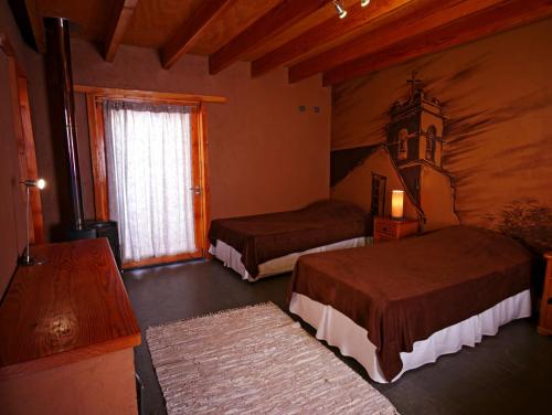 a hotel room with two beds and a window at Terra Luna Atacama in San Pedro de Atacama
