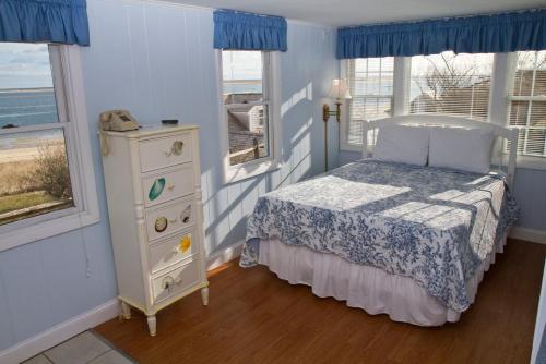 a bedroom with a bed and a dresser and windows at The Hawthorne in Chatham