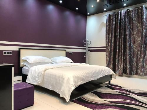 a bedroom with a bed and a purple wall at Deluxe Furnished Apartments in Taif