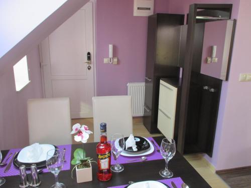 a dining room with purple walls and a table with plates and glasses at Alpha Apartman Sárvár in Sárvár