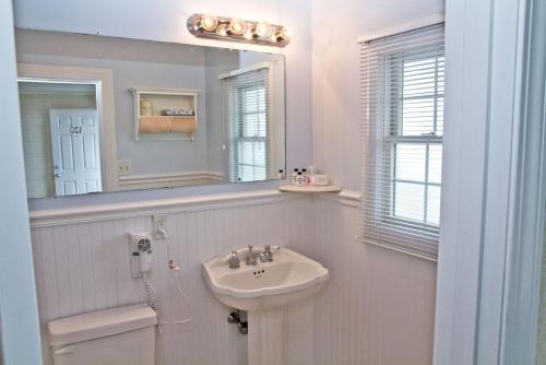 uma casa de banho branca com um lavatório e um espelho em The Hawthorne em Chatham