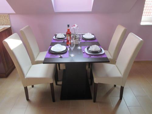 a dining room table with white chairs and a purple table at Alpha Apartman Sárvár in Sárvár