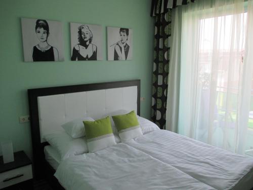 Alpha Apartman Sárvár في شارفار: غرفة نوم بسرير ابيض مع وجود صورتين على الحائط