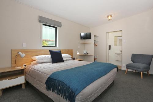 a bedroom with a bed and a desk and a chair at Shakespeare House in Te Anau