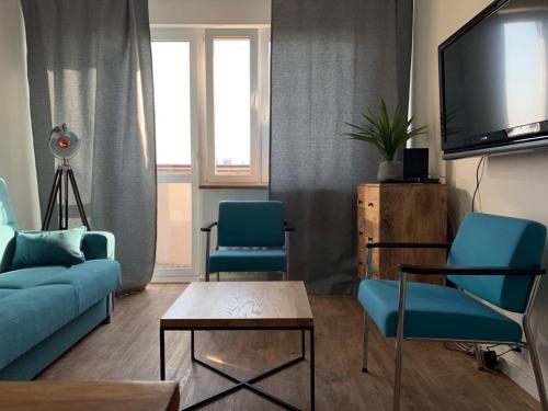 a living room with two blue chairs and a tv at Fok Sztormowy in Hel