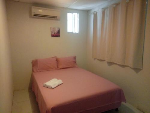 a small bedroom with a pink bed with a window at Casa da Esquina Pousada in Recife