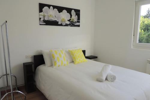 Un dormitorio con una cama blanca con almohadas amarillas y blancas en Precioso piso en Oviedo, Parking, Wifi y Netflix By DeLabra Apartments, en Oviedo