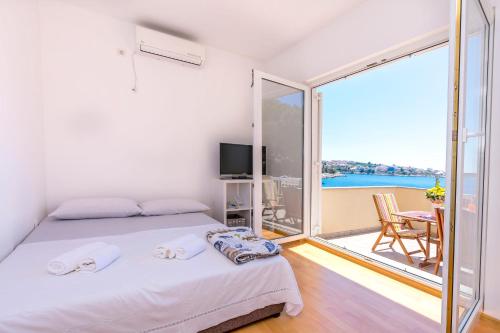 a white bedroom with a bed and a balcony at Apartments Ive i Maja in Ražanj