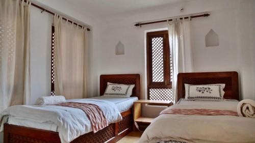 1 dormitorio con 2 camas y ventana en Sunny Guest House and Cafe, en Bhaktapur