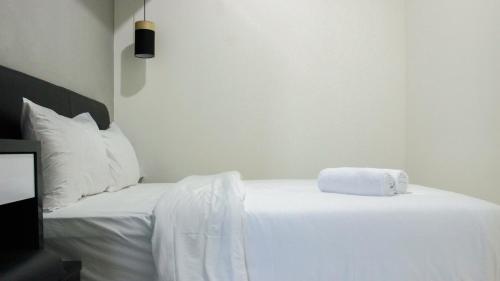 a white bed with a towel on top of it at Direct Access to Pool 2BR Apartment at Parahyangan Residence By Travelio in Bandung