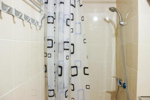 a bathroom with a shower with a white shower curtain at Direct Access to Pool 2BR Apartment at Parahyangan Residence By Travelio in Bandung