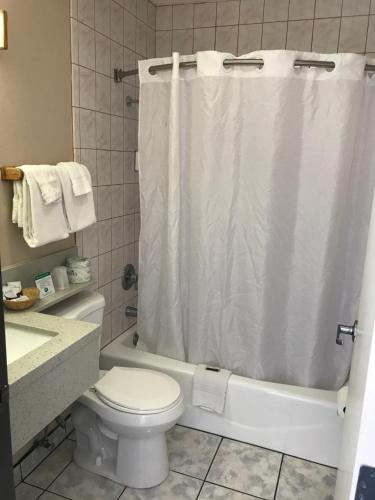 a bathroom with a white shower curtain and a toilet at Manhattan Inn & Suites in Manhattan Beach