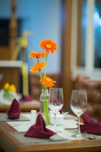 a table with two glasses and a vase with orange flowers at Hanoi Amber Hotel in Hanoi