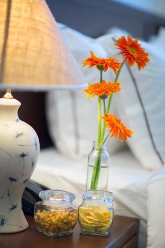 a table with a vase with flowers and two glass jars at Hanoi Amber Hotel in Hanoi