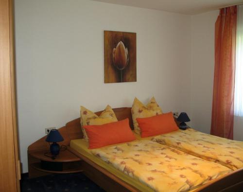 a bedroom with a bed with orange and yellow pillows at Ferienwohnung Schneemann in Valwig