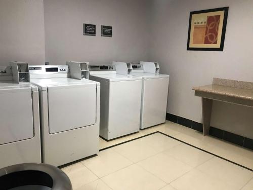 three washers and dryers are lined up in a room at West Valley Inn in West Valley City