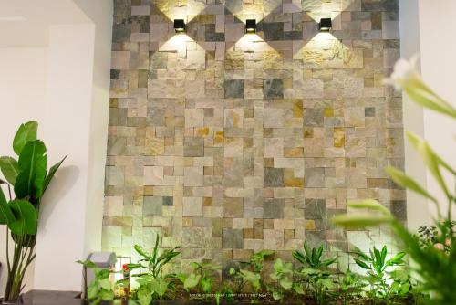 a brick wall with lights in a room with plants at Lama Homestay in Hue