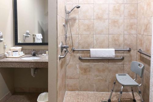 a bathroom with a shower with a sink and a chair at Comfort Suites Beaumont I-10 in Beaumont