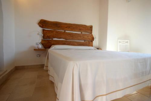 a bedroom with a bed with a wooden headboard at Home Holiday Salento Casa Belvedere in Specchia