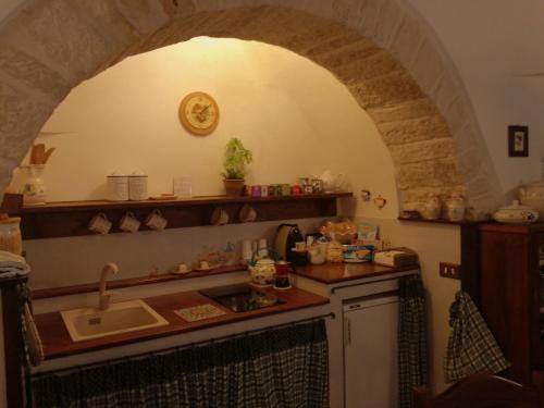 uma cozinha com um lavatório e um balcão com um arco em Miratrulli Apartment & Trullo dell'Aia em Alberobello