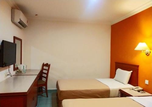 a hotel room with two beds and a desk at Megah Inn in Kota Kinabalu
