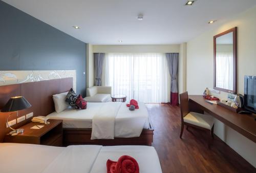 a hotel room with two beds and a desk at Grand Jomtien Palace Hotel - SHA Extra Plus in Jomtien Beach