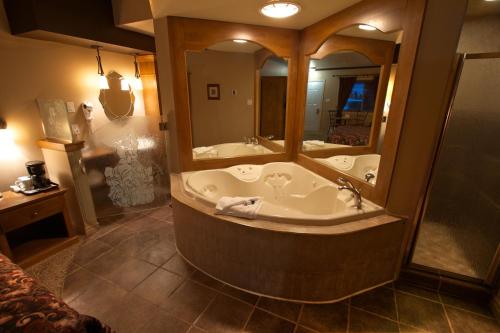 ein großes Bad mit einer Badewanne und einem großen Spiegel in der Unterkunft Hotel-Motel Drummond in Drummondville