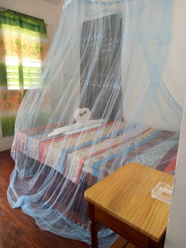 a bed covered in plastic with a wooden table at Jeno Tourist Inn in San Vicente