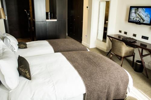 a hotel room with two beds and a desk and a television at Sofitel Montevideo Casino Carrasco & Spa in Montevideo