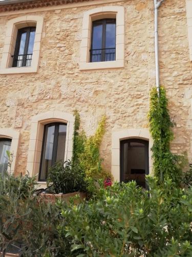 a stone building with windows and plants in front at Domaine de la Vidalle in Vendres