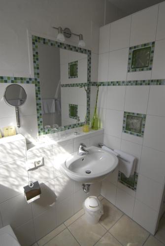 a white bathroom with a sink and a mirror at Weinhotel / Gasthaus zur Sonne in Ihringen