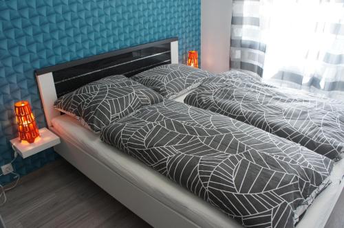 a bed with gray and white comforter and pillows at Laguna Beach Apartmanok in Siófok