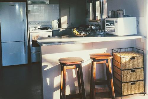 a kitchen with two wooden stools at a counter at Firstcast Turangi in Turangi