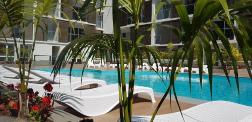 a hotel pool with white chairs and palm trees at Madalenas Palace - Sunrise in Funchal